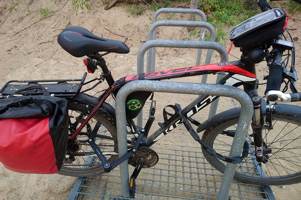 Jak zabezpieczyć rower przed kradzieżą?|Prawidłowo zabezpieczony rower, blokada składana (szekle) oraz łańcuch przypięte do solidnego stojaka rowerowego, zapięcia dodatkowo chronią obydwa koła